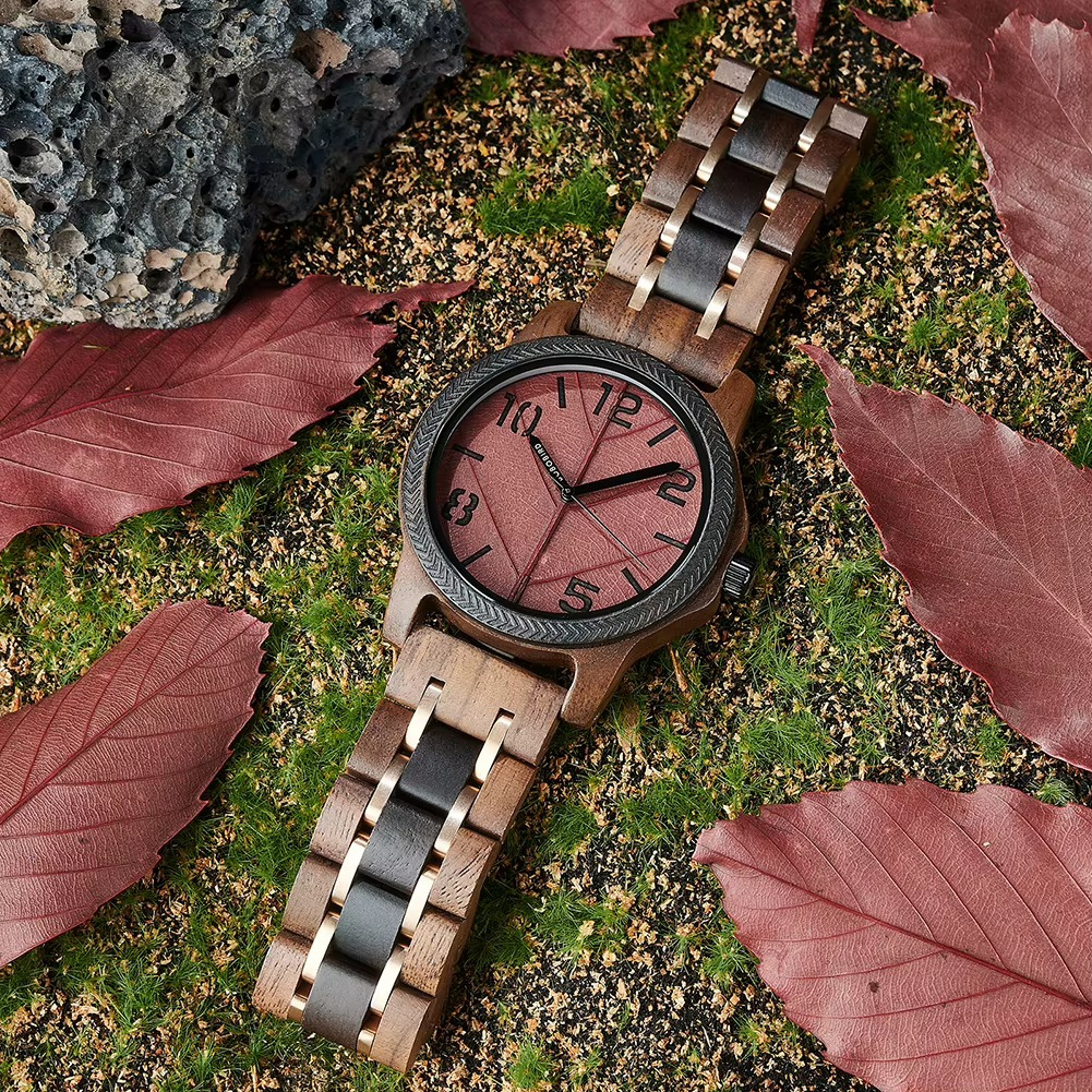 Montre Ambre en bois de noyer avec cadran motif feuille rouge et lunette noire sur bracelet en bois bicolore