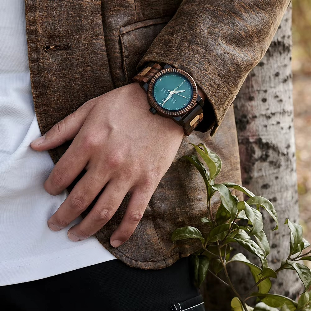 Montre en bois Cordoba avec lunette cannelée, cadran bleu affichant jour de la semaine et date, portée au poignet d'une personne en veste marron