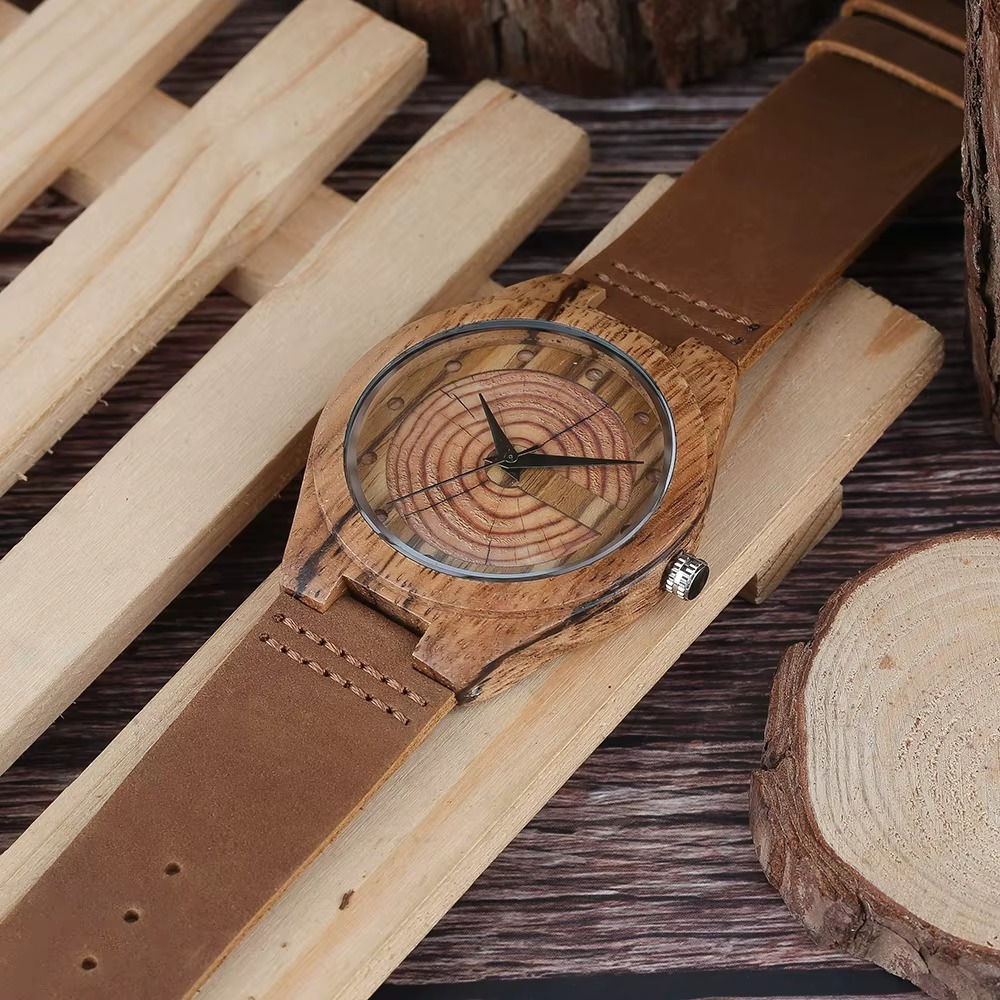 Montre en bois faite main pour homme avec cadran en cernes d'arbre et bracelet en cuir camel posée sur des planches en bois clair