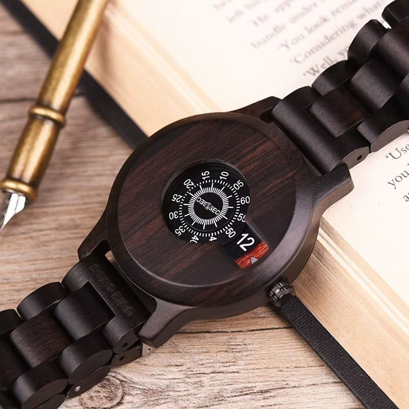 Montre en bois homme ébène Mystère avec affichage à disques rotatifs sans aiguilles vue de face sur un livre