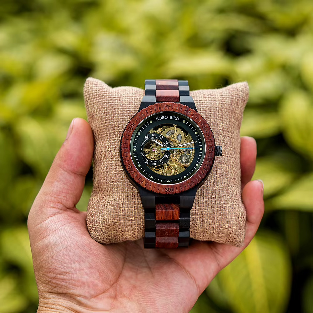 Montre en bois mécanique homme Kaïro avec cadran squelette visible et bracelet en bois bicolore tenue en main