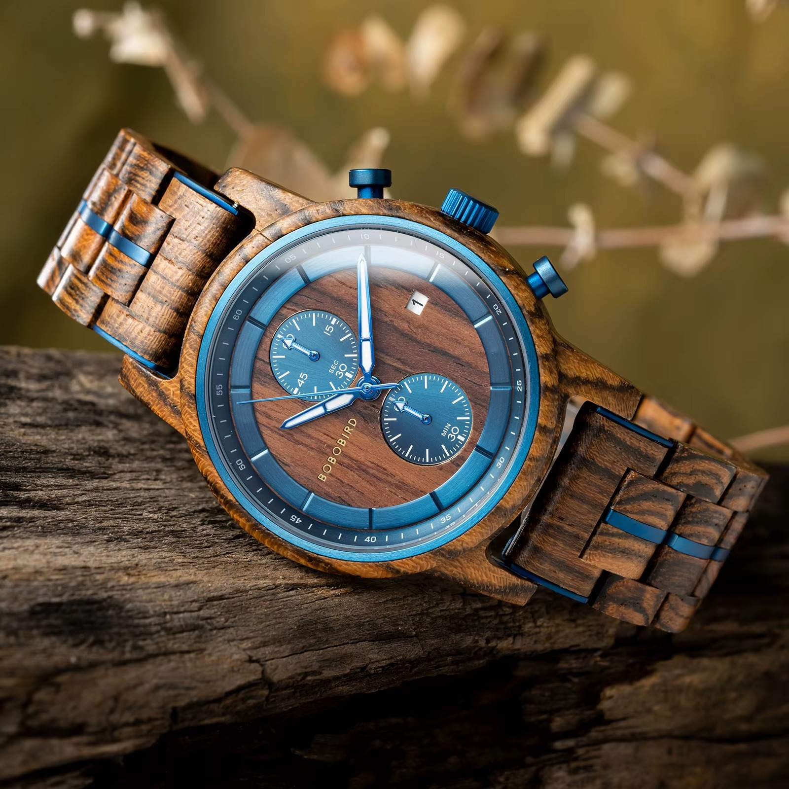 Montre Delphes en bois d'olivier et ébène avec cadran chronographe bleu et bracelet en bois, vue en gros plan sur un support en bois