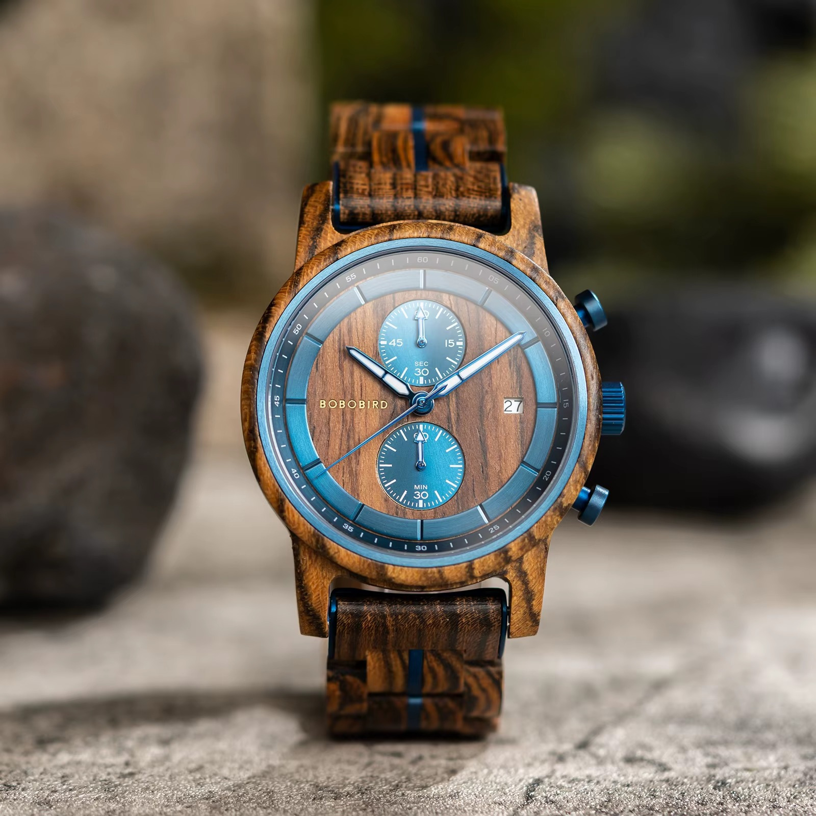 Montre Delphes en bois d'olivier et ébène avec cadran chronographe étanche 3 atm vue de face sur fond flou