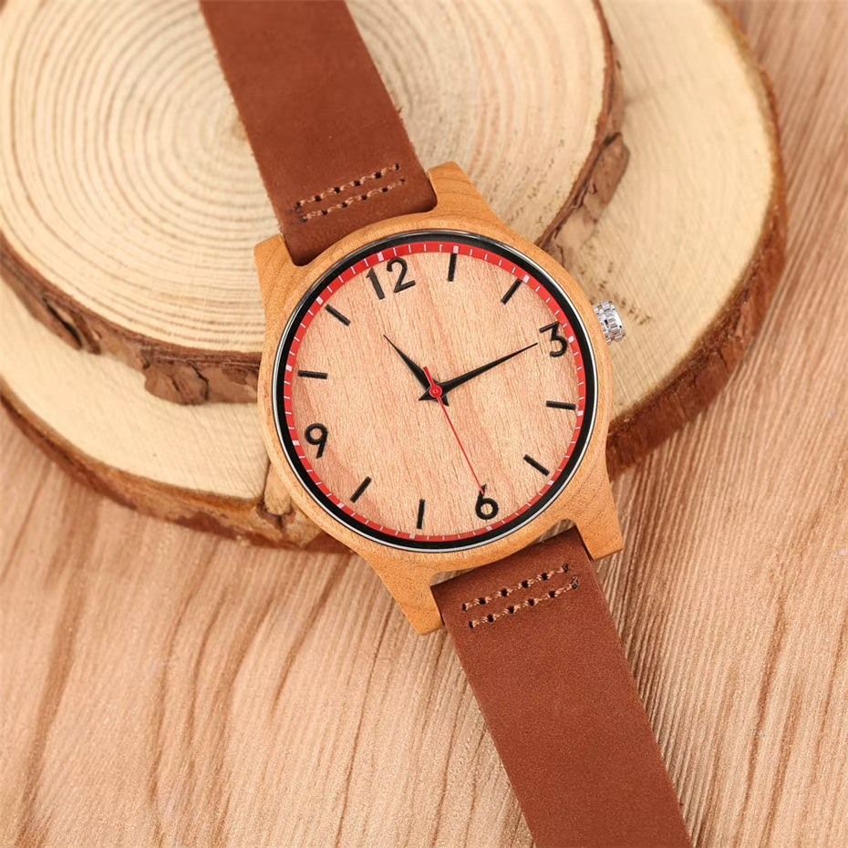 Montre Hanami en bois minimaliste avec cadran cerclé rouge et bracelet en cuir marron posée sur rondins de bois