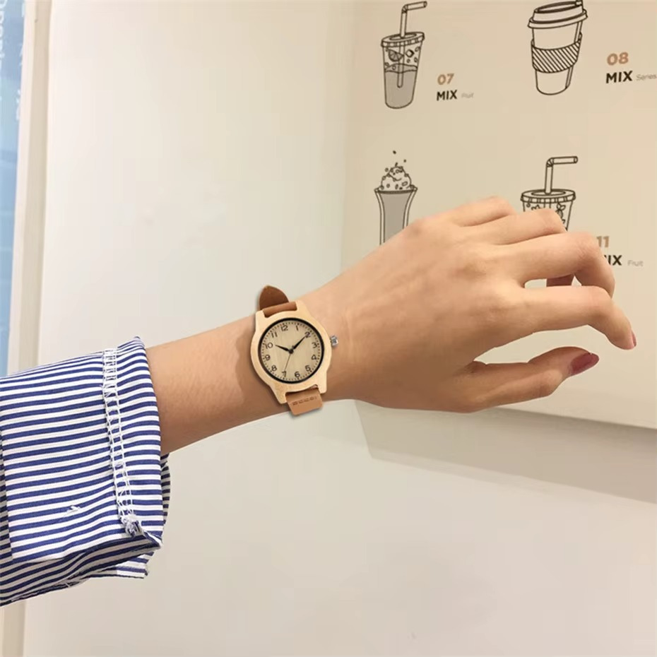 Montre Toscane en bois de bambou pour femme avec bracelet en cuir souple marron portée au poignet